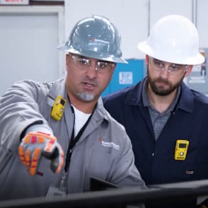 Field technicians discussing PWHT services preheat weld treatment on a pipe.