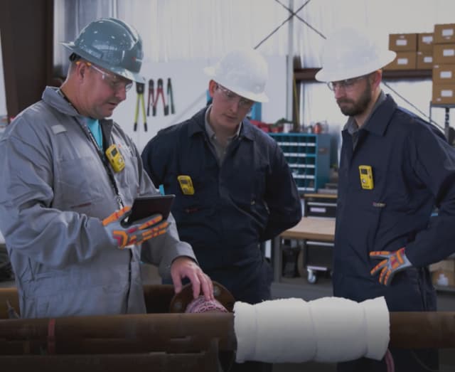 Field technicians reviewing preheat weld treatment and PWHT services on a pipe.
